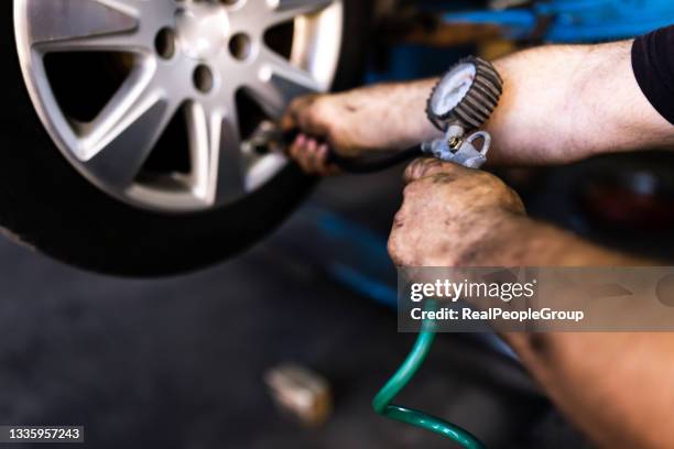 close up of mechanic's hand checking the air pressure of a tyre in auto repair service - nitrogen stock pictures, royalty-free photos & images