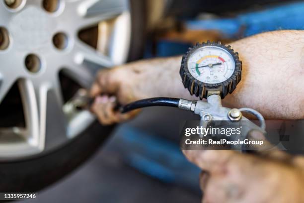 close up of mechanic's hand checking the air pressure of a tyre in auto repair service - physical pressure stockfoto's en -beelden