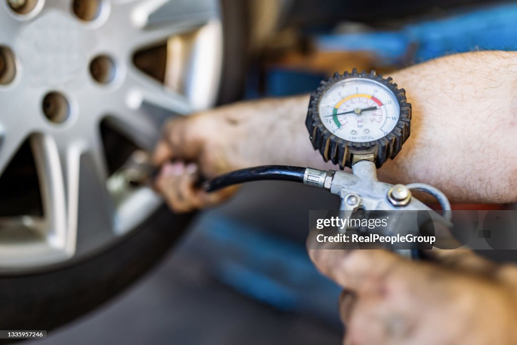 Close up of mechanic's hand checking the air pressure of a tyre in auto repair service