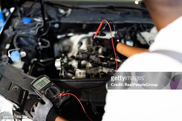 autoelektriker bei der fehlerbehebung eines automotors - autobatterie stock-fotos und bilder