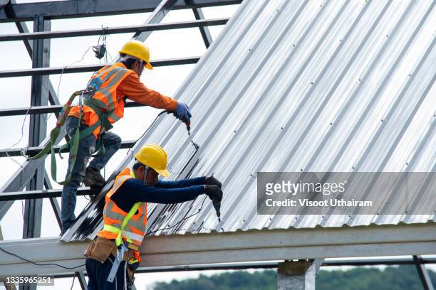 construction worker install new roof of building on construction site. - workers compensation stock pictures, royalty-free photos & images