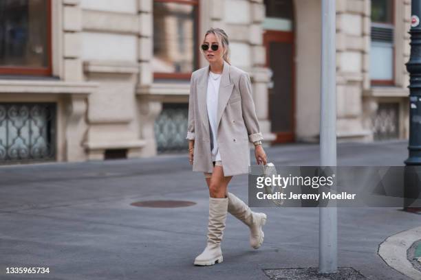 Christina Biluca wearing white shirt, beige blazer, white bag, black shades and beige Copenhagen knee-high boots on August 03, 2021 in Munich,...