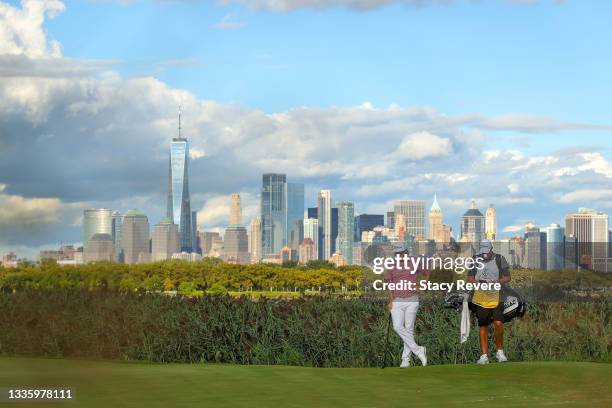 Cameron Smith of Australia waits with his caddie Sam Pinfold on the 14th green as the NYC skyline is seen in the distance during the final round of...