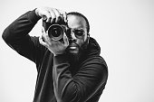 Professional photographer at the studio, African American man wear black hoodie and sunglasses with digital camera is working. Black and white concept photography