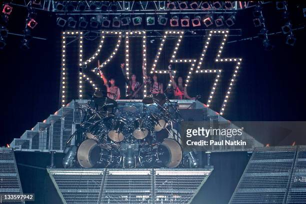 From left, American musicians Eric Carr, Gene Simmons, Bruce Kulick, and Paul Stanley of the group Kiss wave from the stage at the Mecca Arena,...