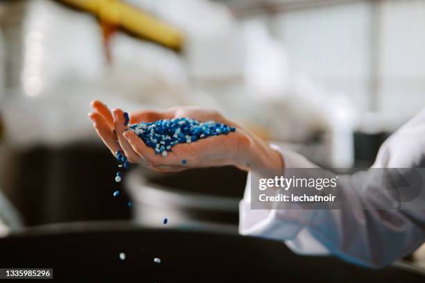 female technician inspecting pellets made of biodegradable materials - granule stockfoto's en -beelden