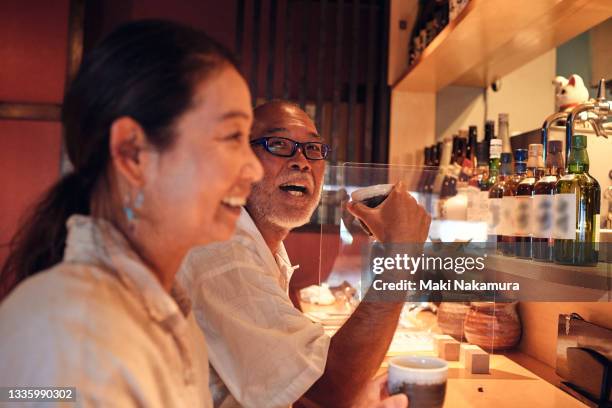 a smiling man sitting at the counter of a restaurant, talking. - japanese respect stock pictures, royalty-free photos & images