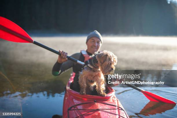 senior man and his terrier dog kayaking on lake - flytväst bildbanksfoton och bilder