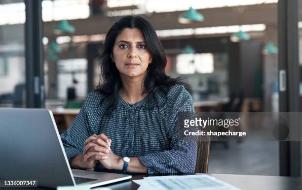 shot of a mature businesswoman using a laptop in a modern office - serious stock pictures, royalty-free photos & images