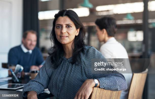 portrait of a mature businesswoman having a meeting with her team in a modern office - 50 year old indian lady stock pictures, royalty-free photos & images