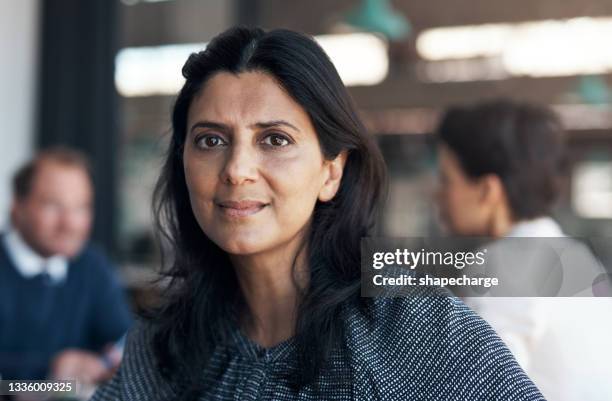 portrait of a mature businesswoman having a meeting with her team in a modern office - 50 year old indian lady stock pictures, royalty-free photos & images