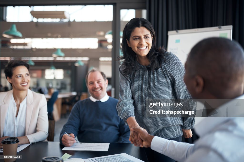Shot of a businesswoman and businessman shaking hands during a meeting in a modern office