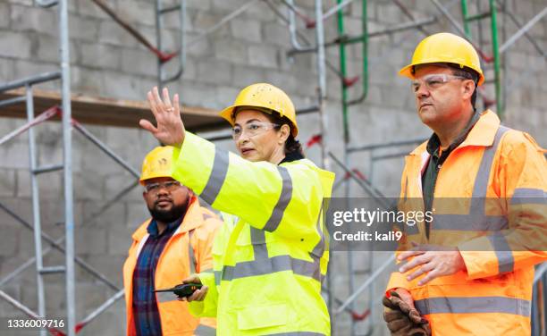 une femme hispanique dirige l’équipe sur le chantier de construction de bâtiments - geste stop photos et images de collection