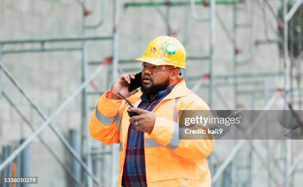 construction worker at job site talking on mobile phone - walkie talkie stock pictures, royalty-free photos & images