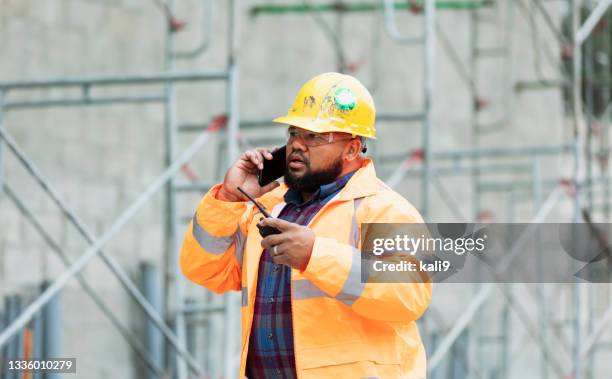 construction worker at job site talking on mobile phone - walkie talkie imagens e fotografias de stock