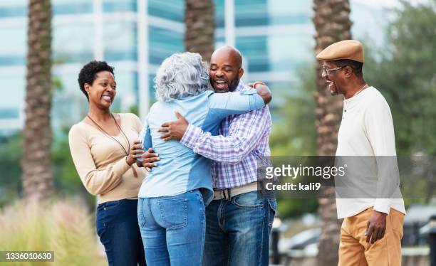 afroamerikanisches familientreffen, seniore frau umarmt sohn - black family reunion stock-fotos und bilder