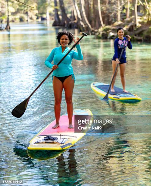 frau und freundin auf stand up paddleboards winken vor die kamera - saia florida stock-fotos und bilder