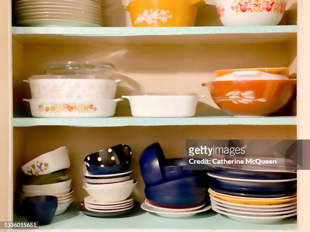 vintage 1950s white wall kitchen cabinets open revealing shelves of old-fashioned kitchenware - vintage crockery stock pictures, royalty-free photos & images