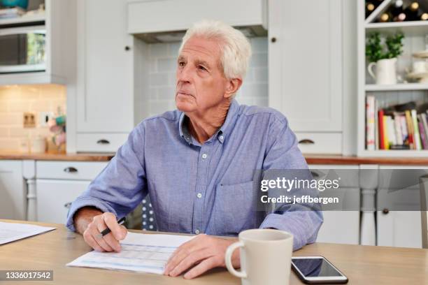 aufnahme eines älteren mannes, der zu hause papierkram durchmacht - banking document stock-fotos und bilder