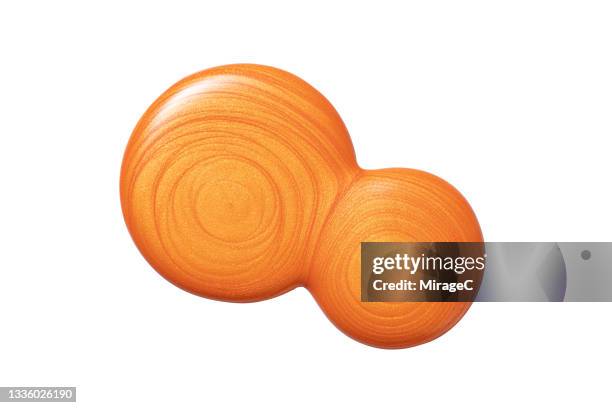 orange nail polish drops merging on white - 2 runde stock-fotos und bilder