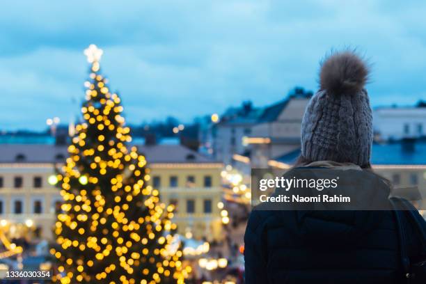 young woman looking at christmas tree lights at helsinki christmas market from rooftop at dusk - christmas finland stock pictures, royalty-free photos & images