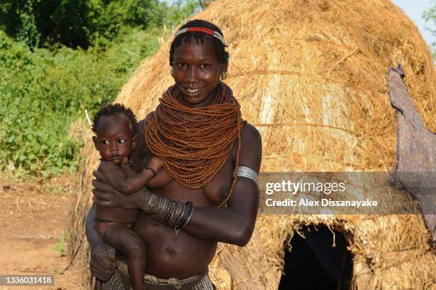 mother of bumi tribe with baby,  with her sweet disposition, seen in front of her home, in lower omo valley, ethiopia - lower omo valley stock pictures, royalty-free photos & images