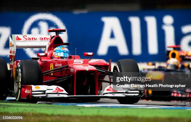Spanish Scuderia Ferrari Formula One team racing driver Fernando Alonso driving his F2012 racing car ahead of the German Red Bull Racing team driver...