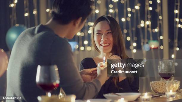 caring boyfriend celebrating his girlfriend's birthday - asian couple dinner stockfoto's en -beelden