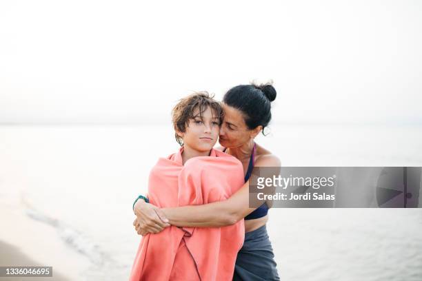 woman and her son embracing on the beach - cute teens stock pictures, royalty-free photos & images