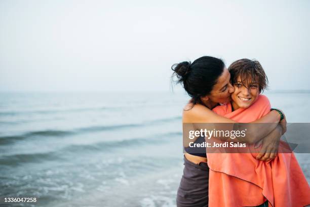 woman and her son embracing on the beach - preteen swimwear bildbanksfoton och bilder