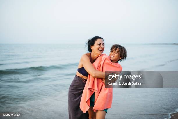 woman and her son embracing on the beach - preteen swimwear bildbanksfoton och bilder