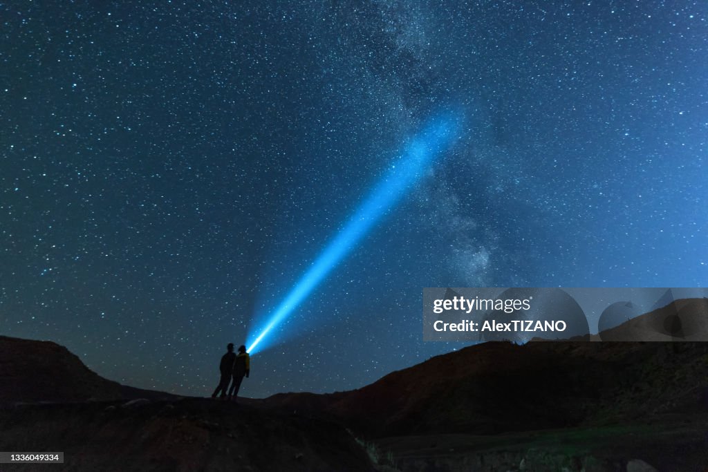 Young couple look toward the galaxy with flashlight