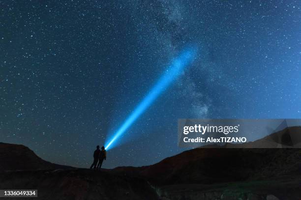 young couple look toward the galaxy  with flashlight - nur erwachsene stock-fotos und bilder