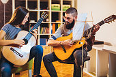 Music teacher tutoring young girl to play guitar at home