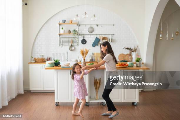 shot of an adorable little girl dancing with her mother at home - family at kitchen fotografías e imágenes de stock