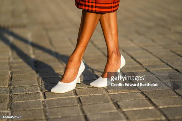 Emilie Joseph @in_fashionwetrust wears a neon orange and black checkered print pattern pencil / tube knees skirt, white leather asymmetric square toe...