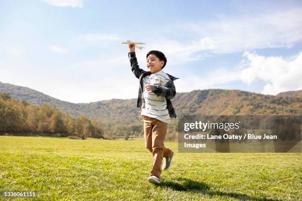 happy chinese boy playing on meadow - model airplane ストックフォトと画像