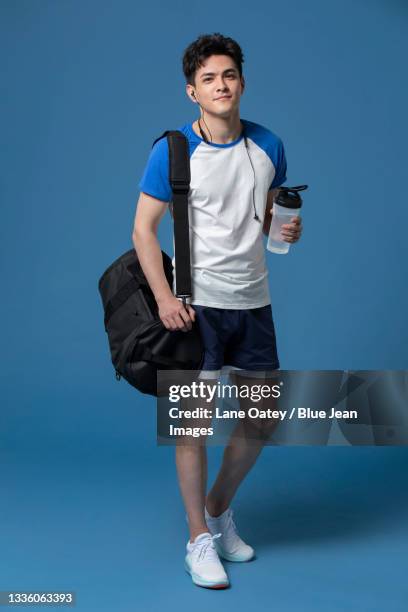 cheerful young chinese athlete holding a bottle of water - duffle bag stock pictures, royalty-free photos & images