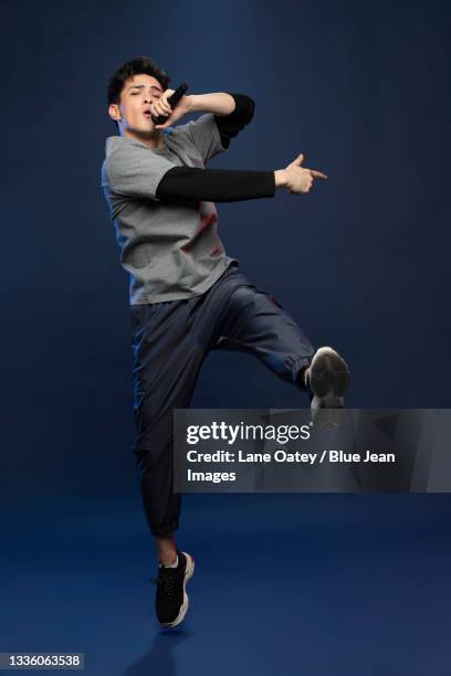 studio shot of fashionable young chinese man singing - nur junge männer stock-fotos und bilder