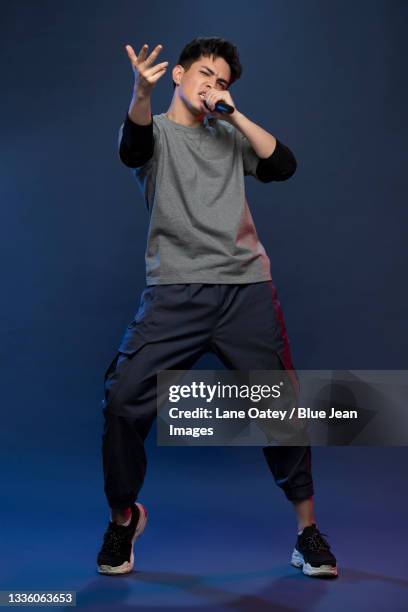 studio shot of fashionable young chinese man singing - asian rapper stock pictures, royalty-free photos & images