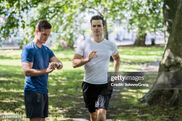 kaukasische männer laufen und timing im sonnigen öffentlichen park - battersea park stock-fotos und bilder