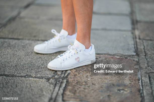 Amanda Derhy wears white with pale pink heart Stan Smith sneakers from Adidas, on August 21, 2021 in Paris, France.