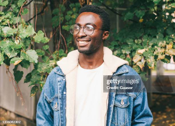 Portrait of happy smiling african man looking away wearing an eyeglasses in autumn city park
