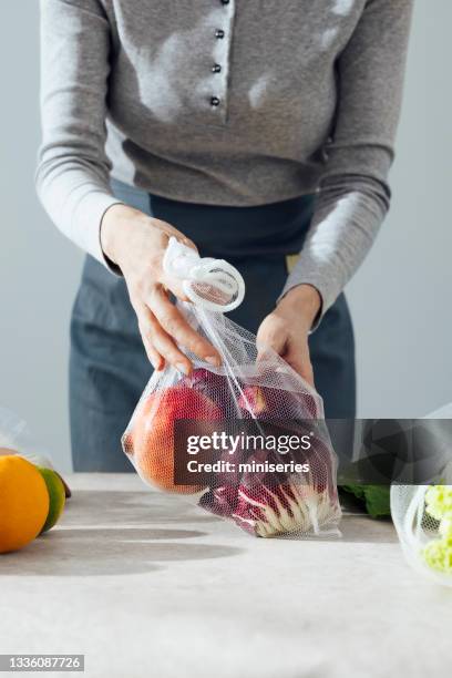 an anonymous woman using mesh bag in kitchen - mesh bag stock pictures, royalty-free photos & images