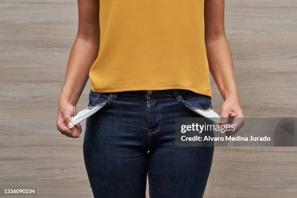 unrecognizable young women showing her empty pockets without money. - povertà foto e immagini stock