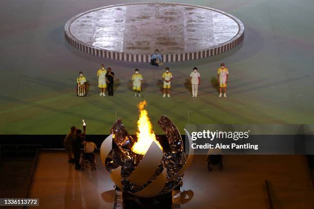 Yui Kamiji , Shunsuke Uchida , Karin Morisaki of Team Japan light the Paralympic flame during the opening ceremony of the Tokyo 2020 Paralympic Games...