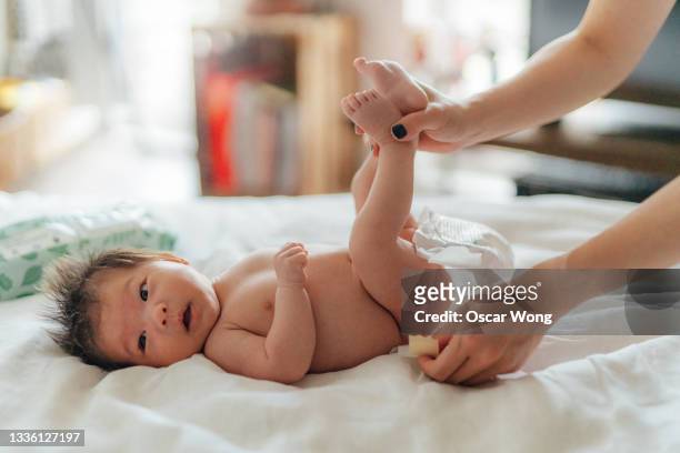 mother taking care of her cute newborn baby - diaper change stock-fotos und bilder