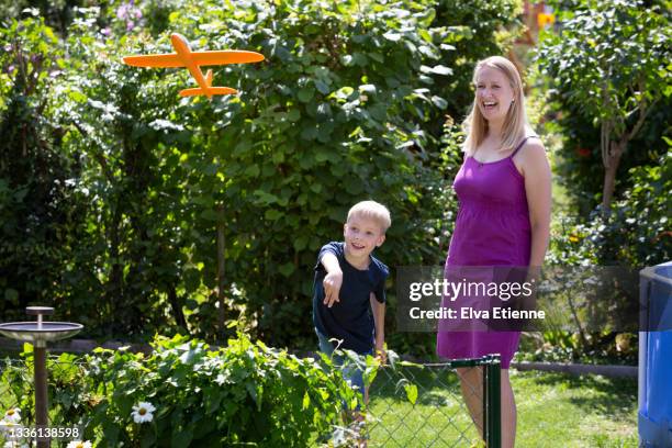 mother and child playing with a toy aeroplane together in an urban garden - zweefvliegtuig stockfoto's en -beelden