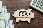 FSA flexible spending account words on wooden piggy bank.