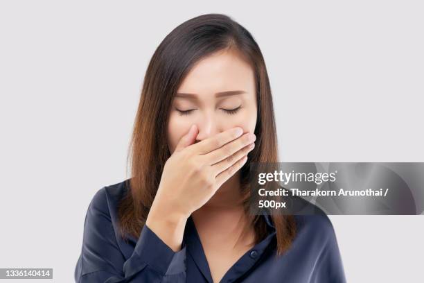 young woman sneezing against white background - bad breath stock pictures, royalty-free photos & images